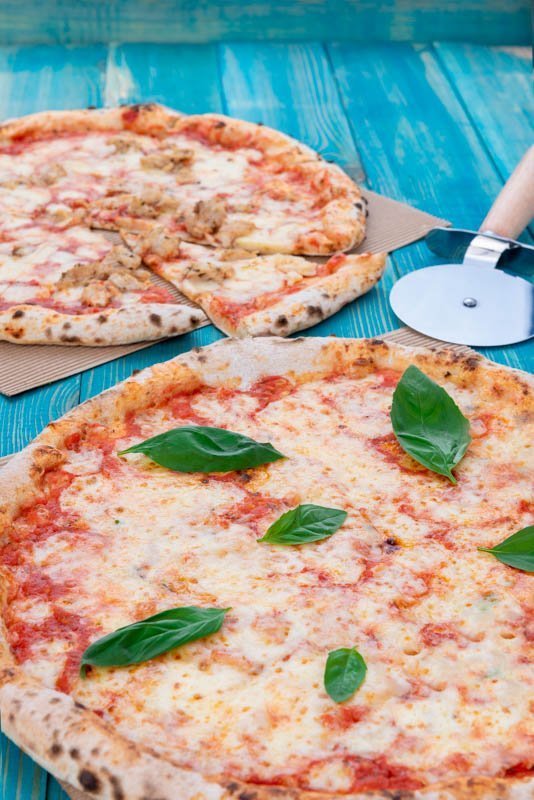 Basil Pizza with Chicken Pizza on Blue Wood Background with Pizza Cutter
